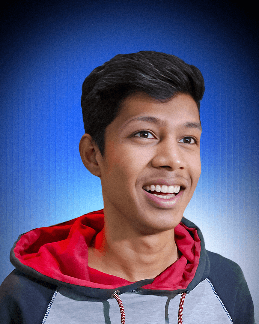 Smiling man in a blue beanie and black hoodie against a brick wall, exuding a joyful and relaxed vibe.