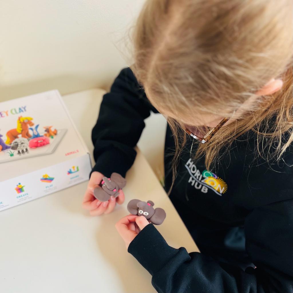 A child is playing with plasticine to make models of elephants faces