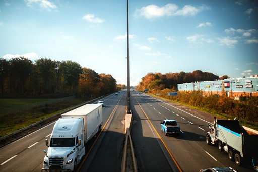 a highway filled with lots of traffic next to a forest
