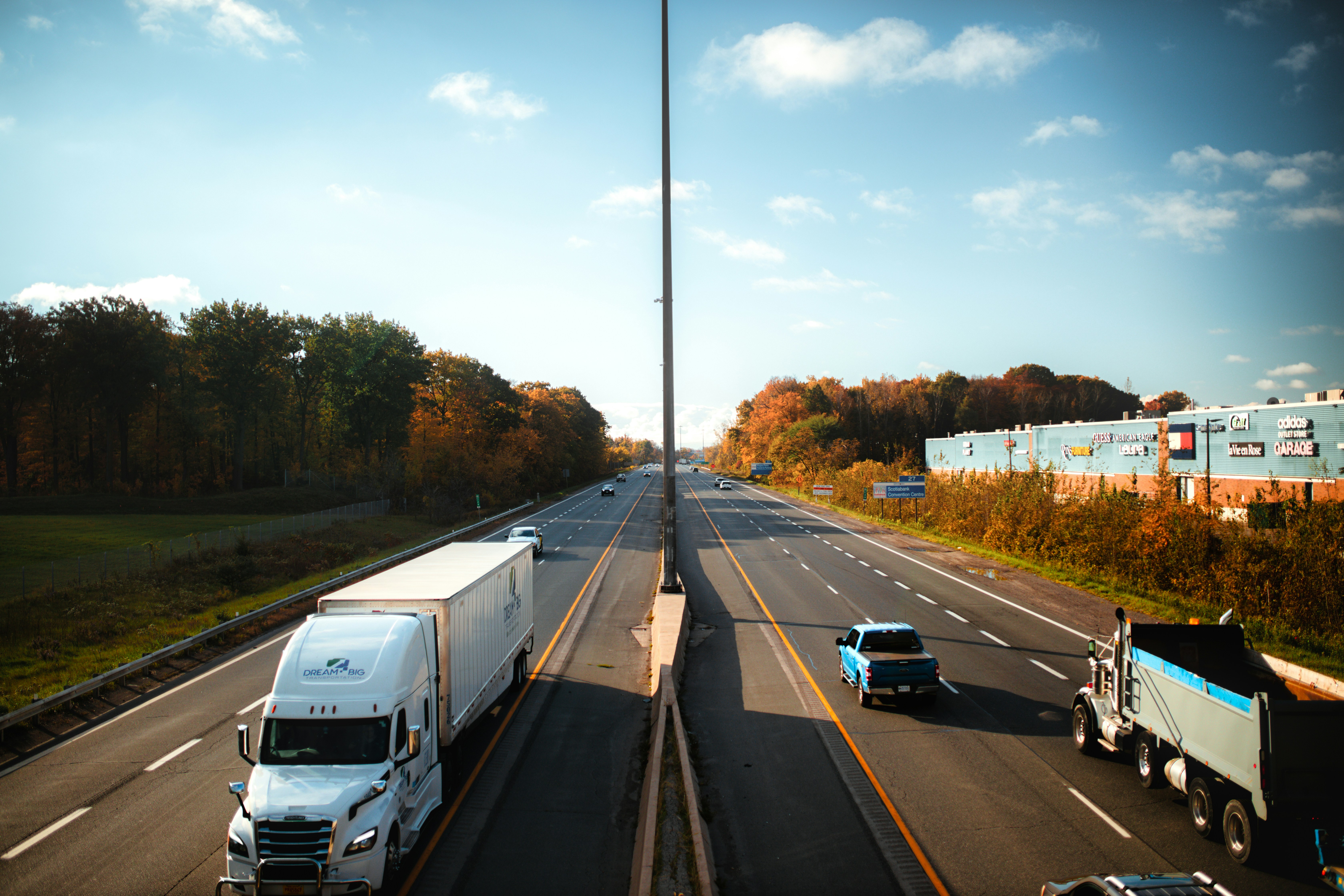 a highway filled with lots of traffic next to a forest