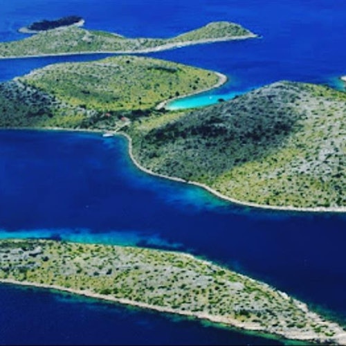 Flygvy över flera gröna, kuperade öar omgivna av djupt blått vatten.