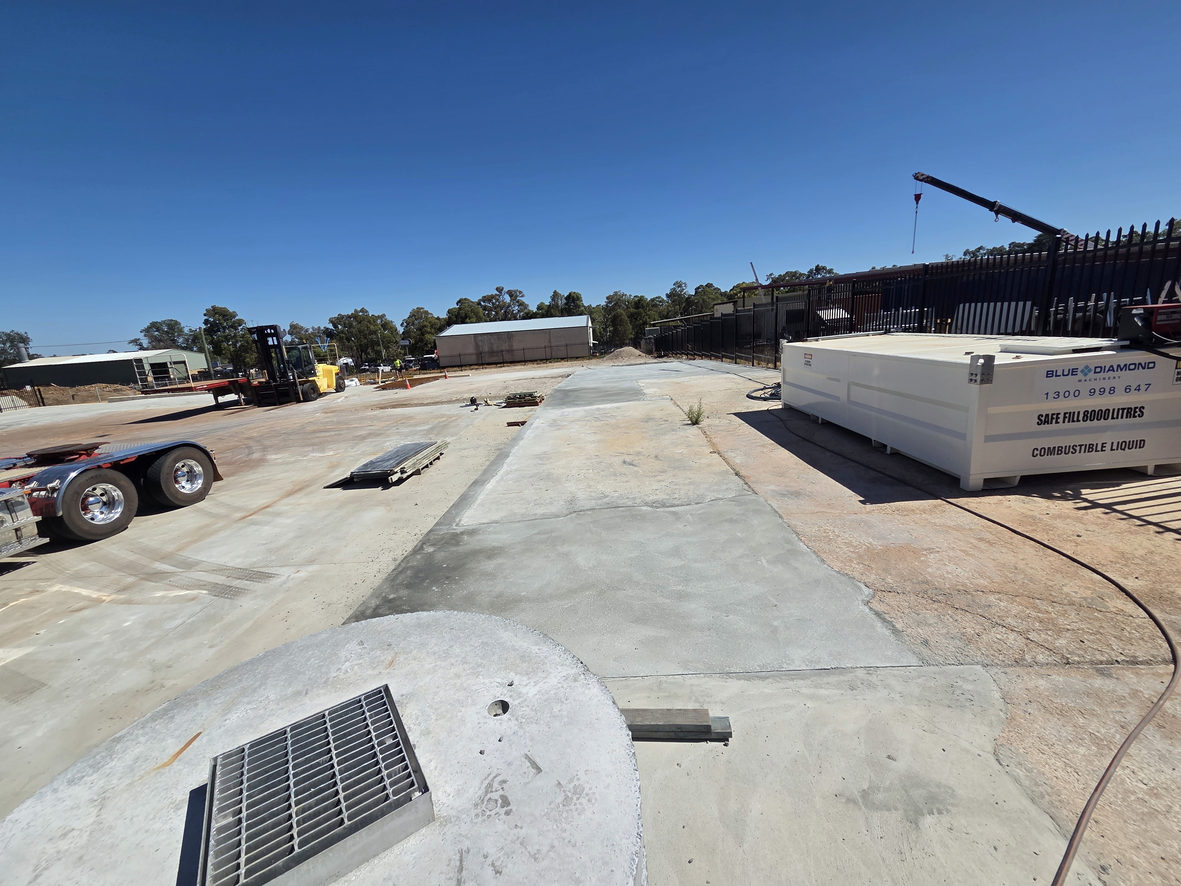 Hand rolls green yoga mat on light surface near plants.