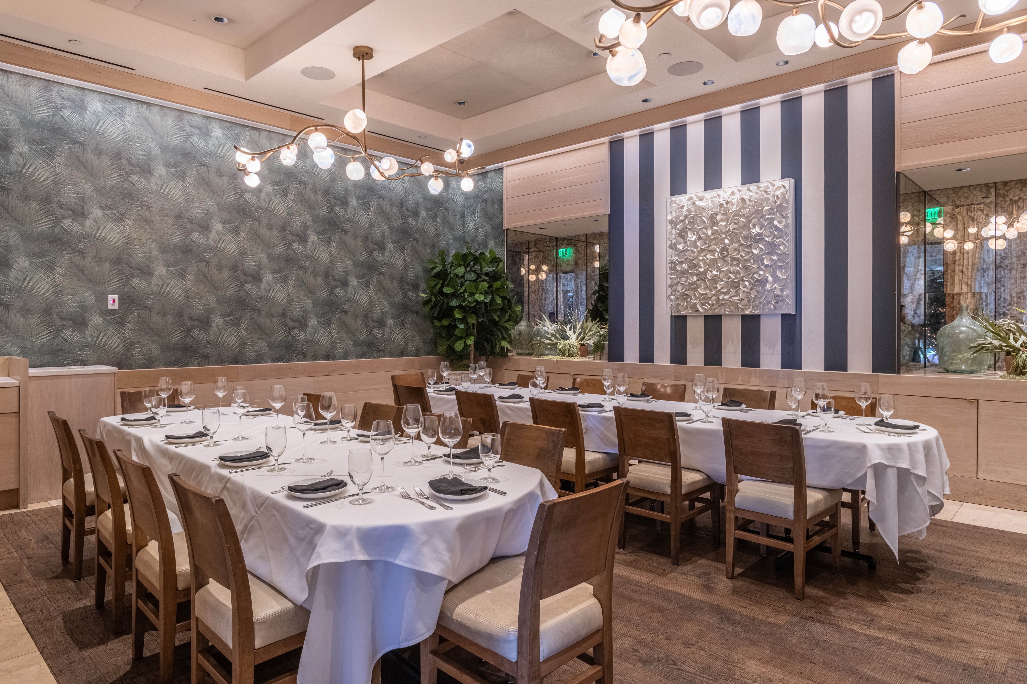 Elegant dining room with a long table set for a meal, featuring decorative walls and soft lighting.