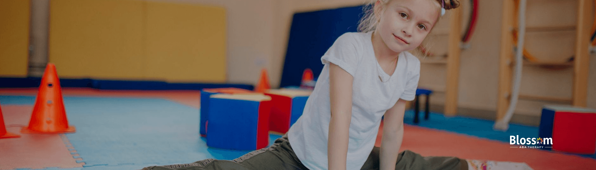 An autistic girl performing a split on a padded floor at a gymnastics training facility in Georgia.