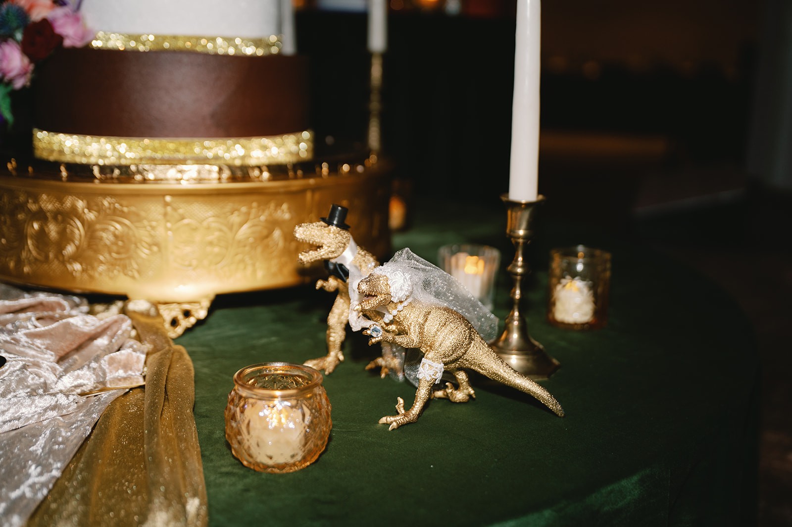 Emerald reception tablescape with floral centerpiece, candles, menus, and dark glassware.