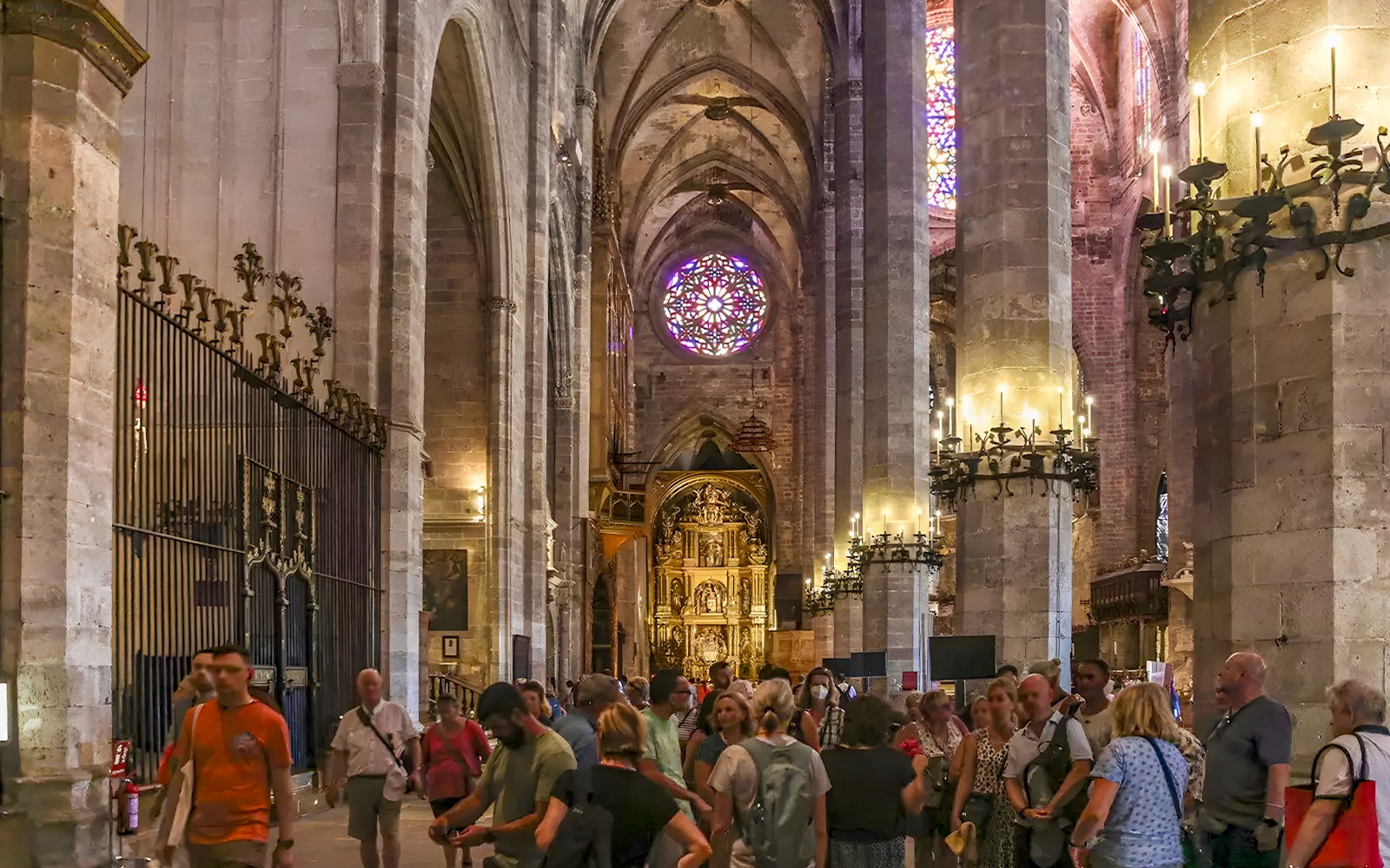 Visitantes dentro de la Catedral de Palma explorando la arquitectura gótica y las vidrieras en Palma, España.