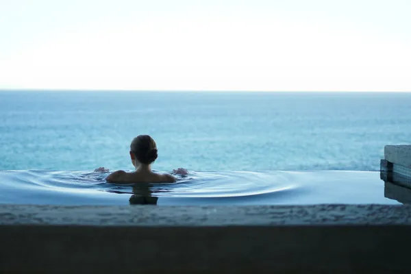Mulher em piscina infinita virada para o mar — transferes hotéis e spas · Táxi Afonso · 06 Caminha