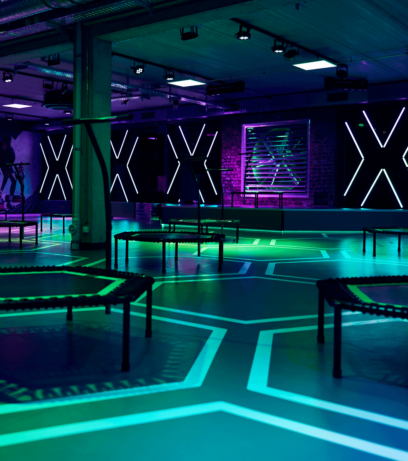 Kursraum von XTRAFIT mit Neonlichtern und Trampolinen, moderner und stylischer Raum.