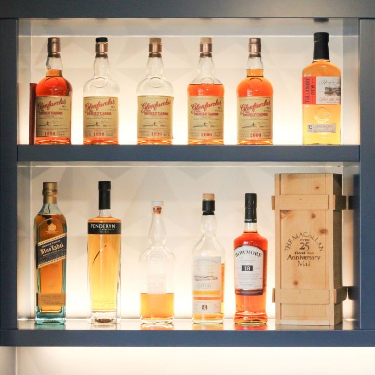 Image of Luxury whiskey and liquor selection on a lit display shelf in a sophisticated home bar area.