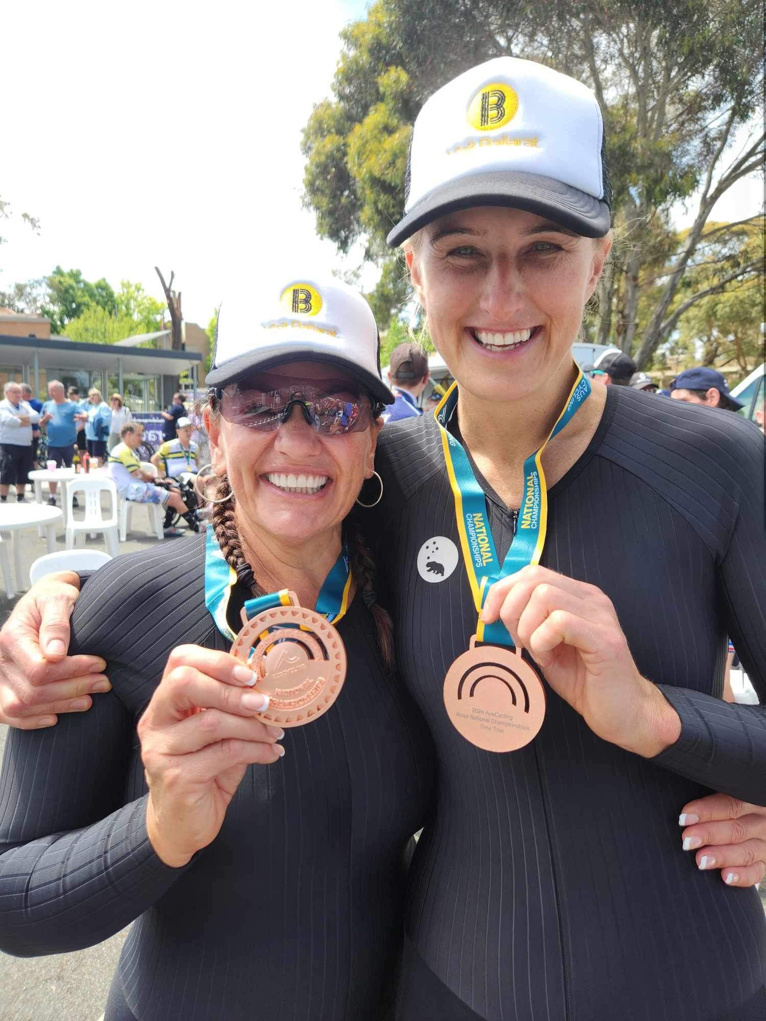 Lily and her pilot, Jay, smiling with their arms around each other, showing their bronze medals