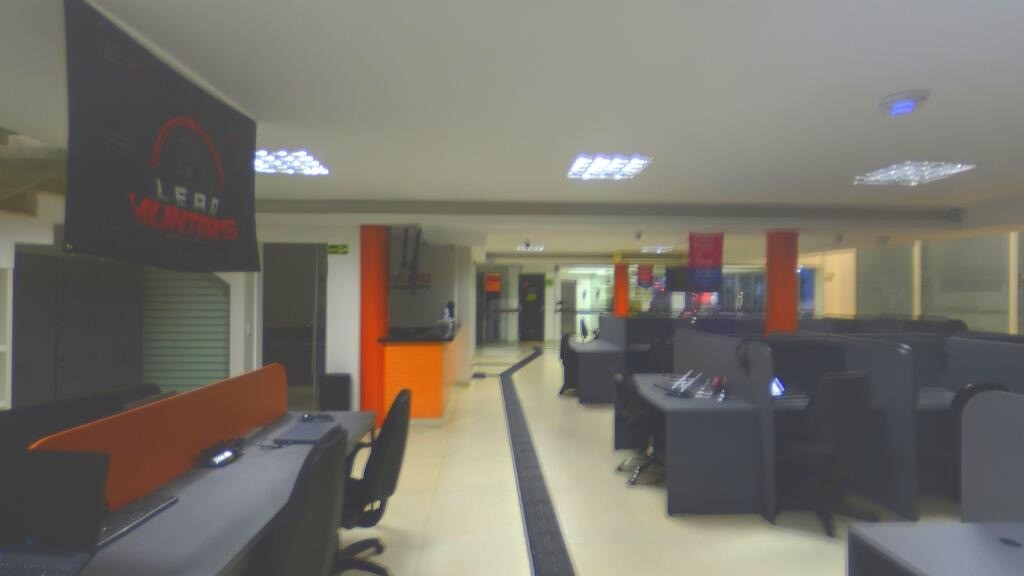 Recepção e área de atendimento da UNEED, com estações de trabalho e pilares laranja