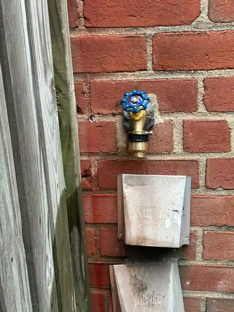 A newly installed exterior utility shutoff valve on a brick wall, completed as part of an outdoor gas line installation service.