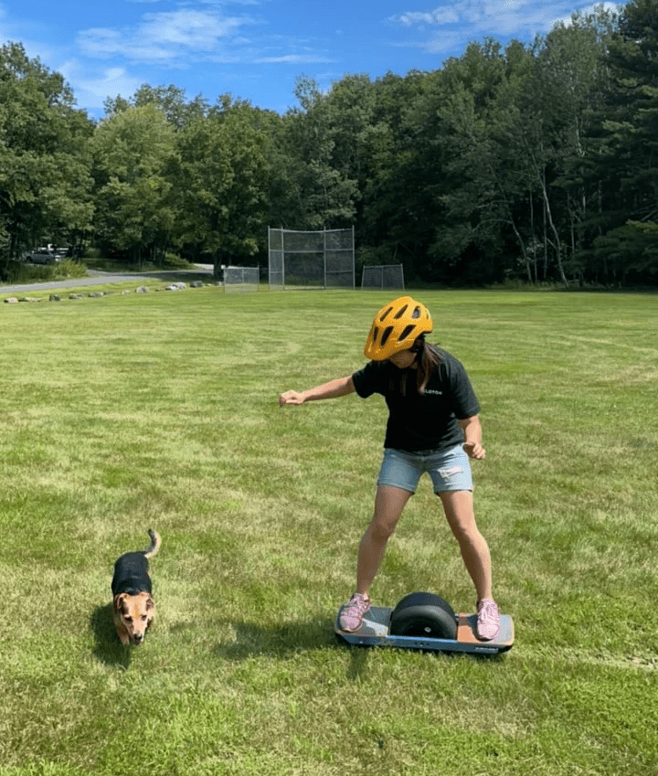 Beagle dog standing next to a woman on one wheel..