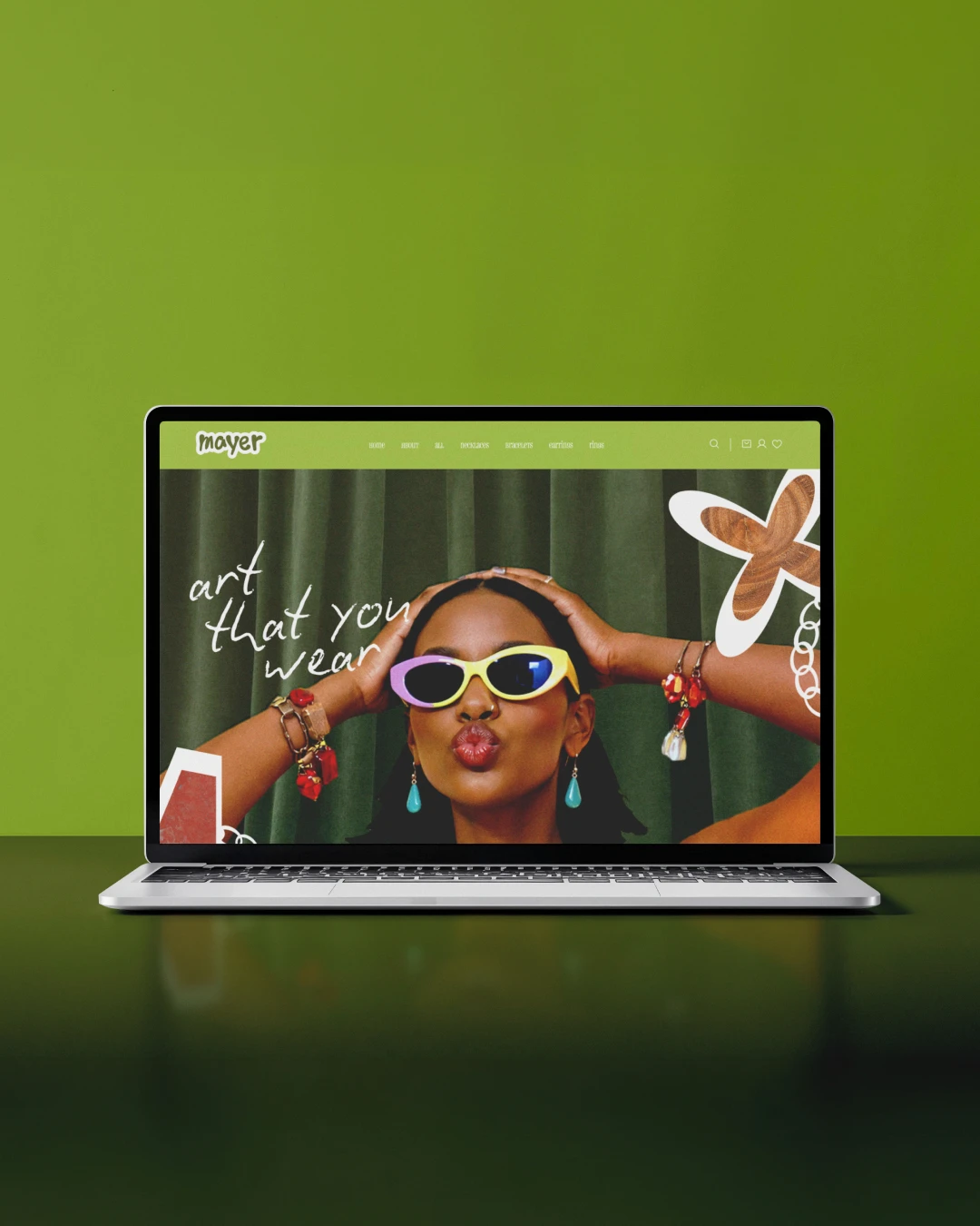 Mockup laptop site e-commerce Mayer Handmade Jewelry — hero pleine page avec modèle et bijoux handmade, tagline manuscrite "art that you wear", UI design identitaire sur fond vert chartreuse, Tartelette Concept Toulouse