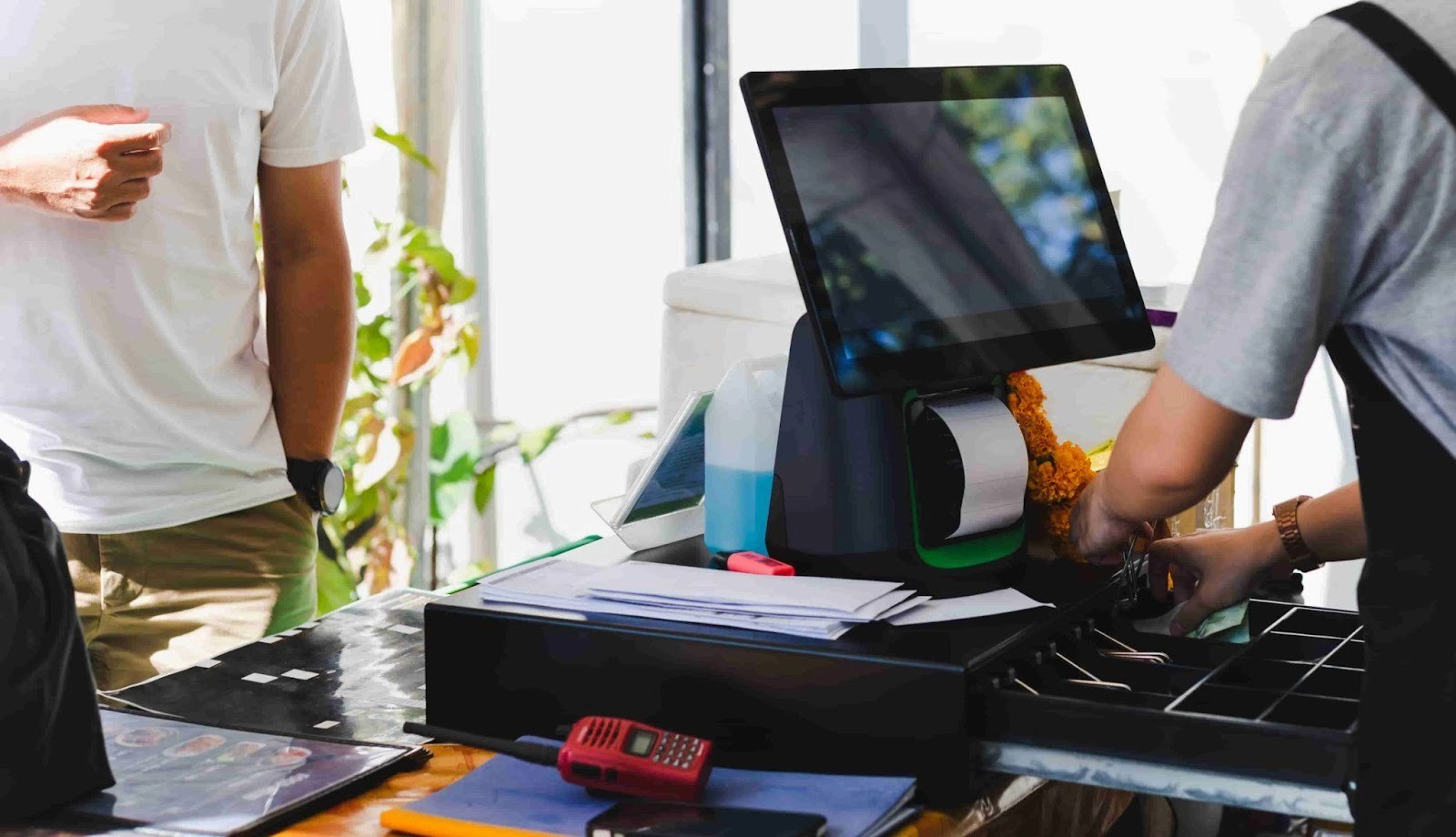 Atendente pegando dinheiro da gaveta de dinheiro na frente de caixa atrás do balcão.