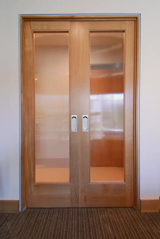Wooden double doors with frosted glass panels in a well-lit room, Irvine Transitional Modern, photo by Chris Darnall.