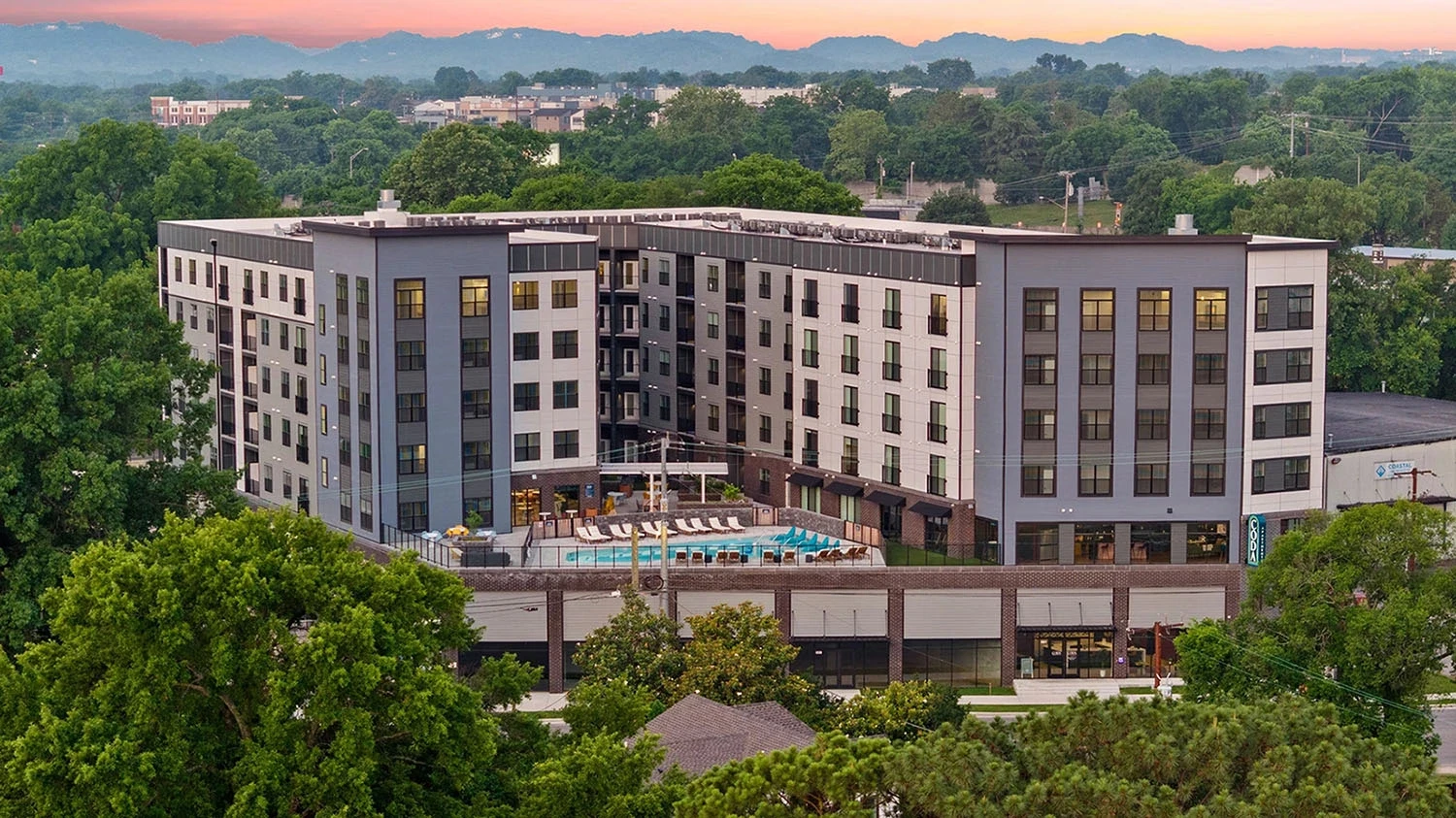 A scenic hotel nestled in the mountains, surrounded by lush greenery and towering peaks.