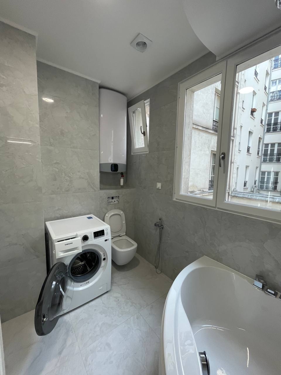 Aménagement de salle de bain avec machine à laver encastrée et carrelage contemporain gris toute hauteur.