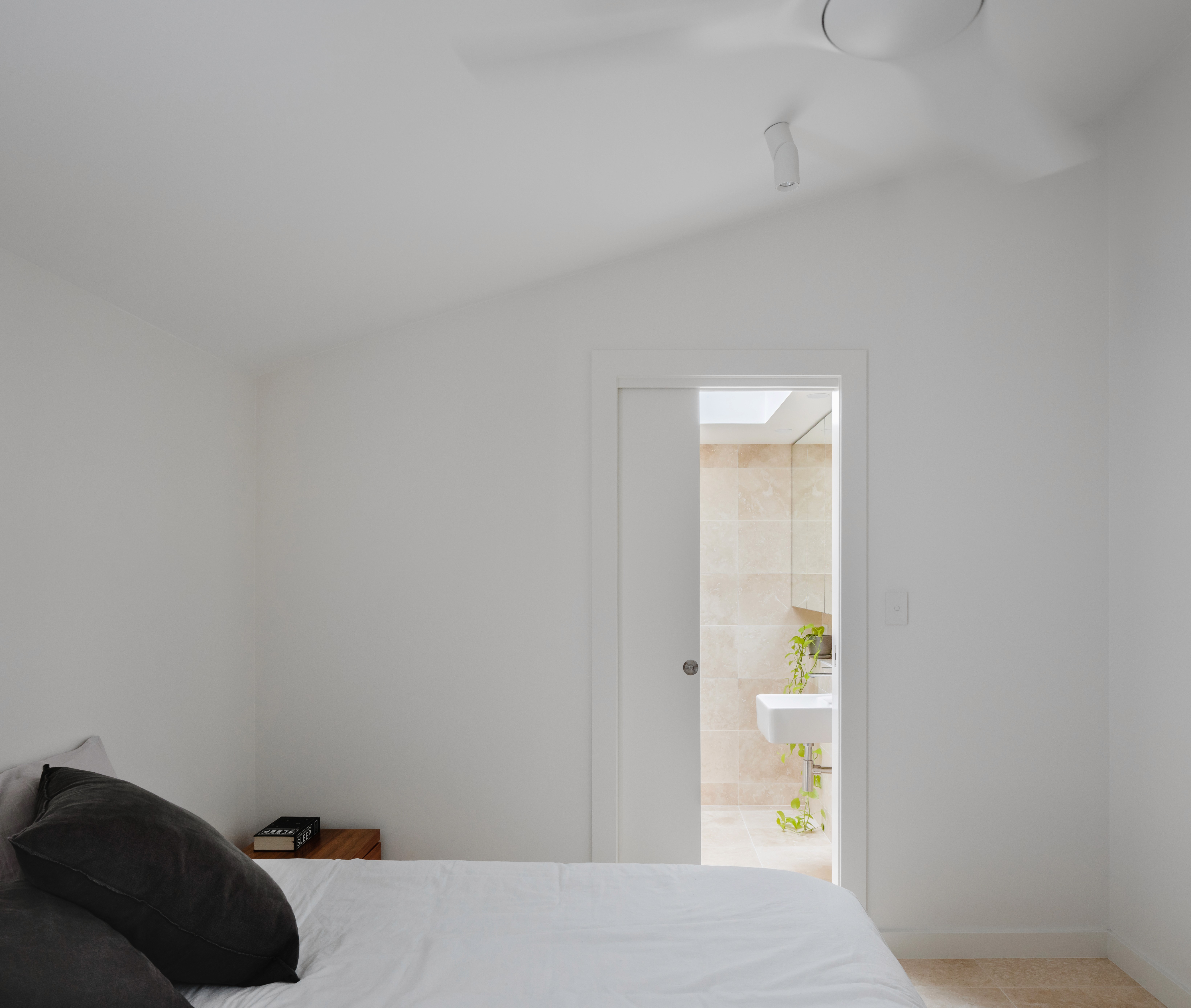 Minimal bedroom inside the Woollahra Treehouse, with white walls, soft natural light, and a quiet connection to the adjacent garden.