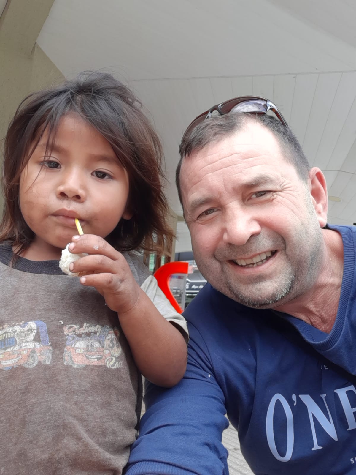 Mujer sentada sobre un tronco frente a una cascada doble en un bosque frondoso de Argentina.