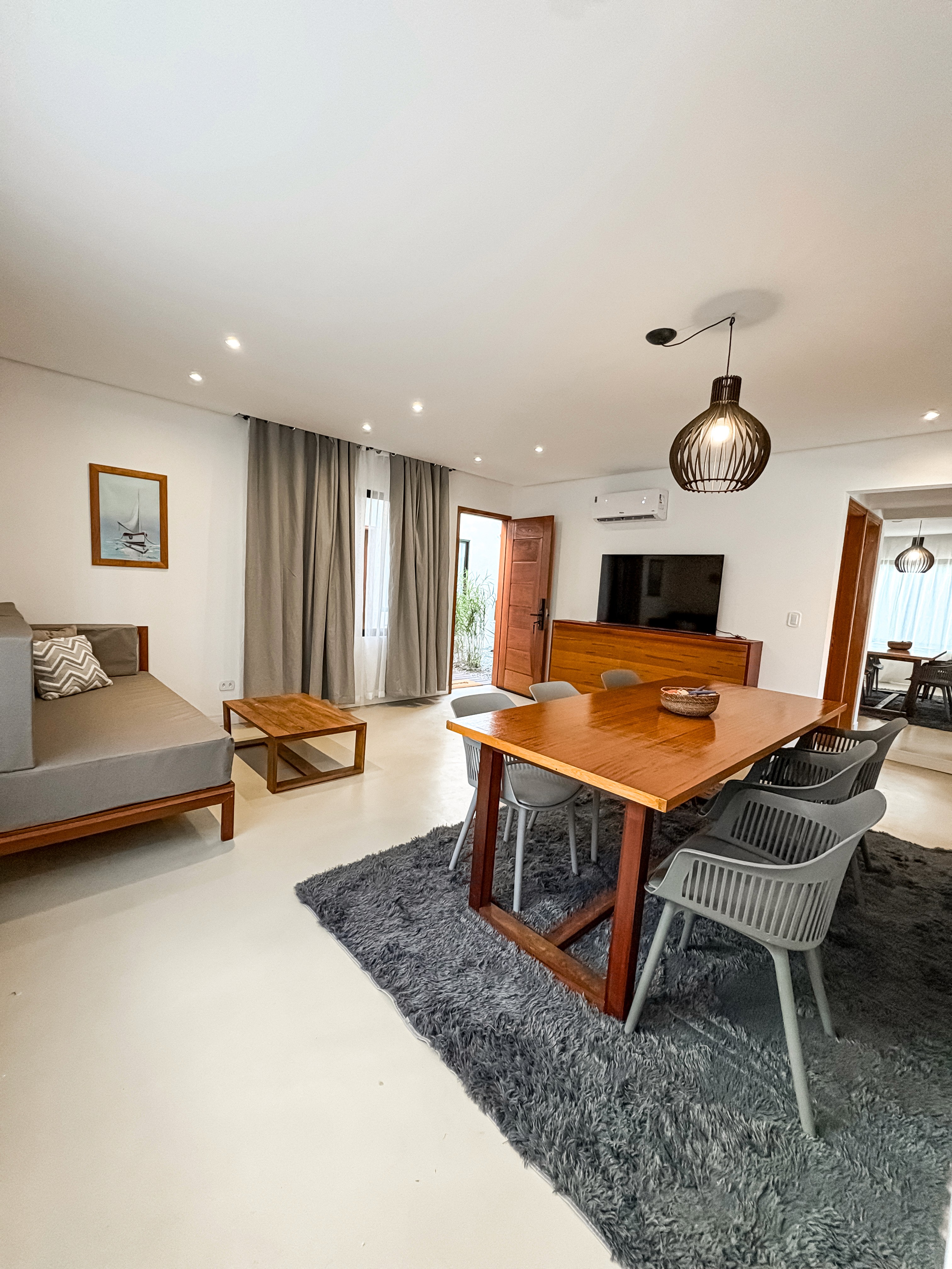 the entire room interior, ocean horizon visible, king bed neatly made, airy curtains flowing in the breeze.