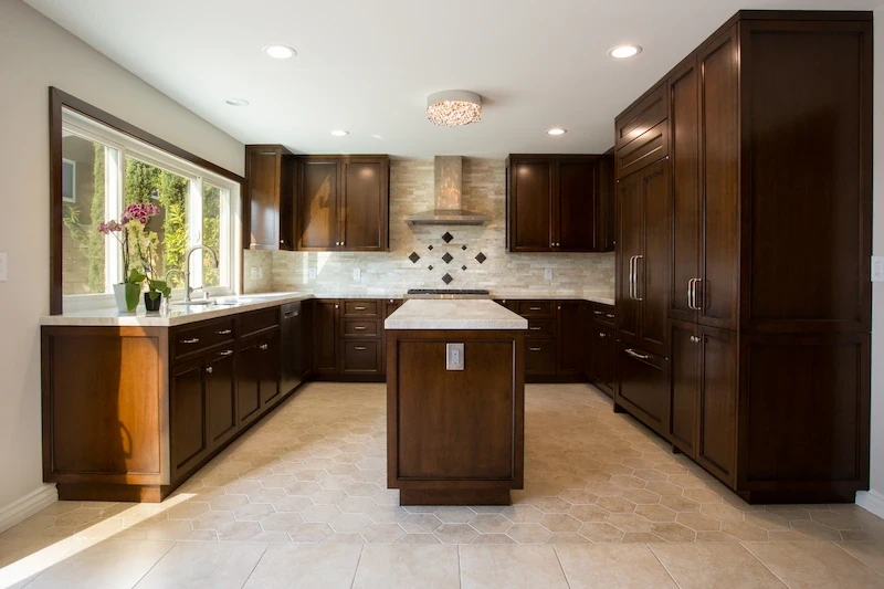 Spacious kitchen with cherry wood cabinets, tile flooring, and island with granite countertop in Orange Interior Remodel.
