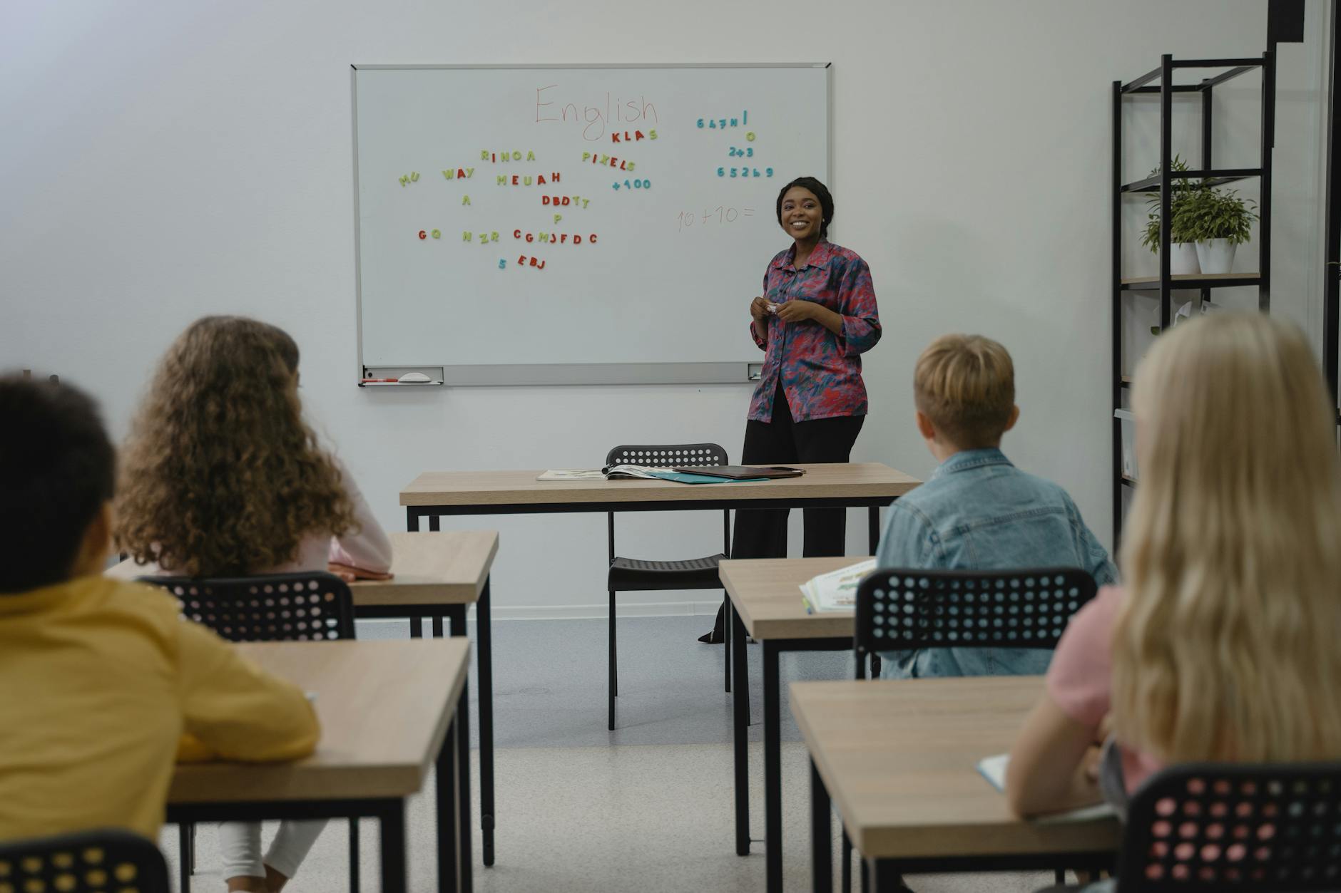A teacher walking between rows of desks, guiding students as they quietly set up their new learning software.