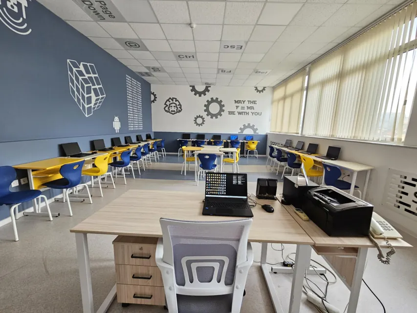 Blue and yellow school chairs in a computer classroom with training tables