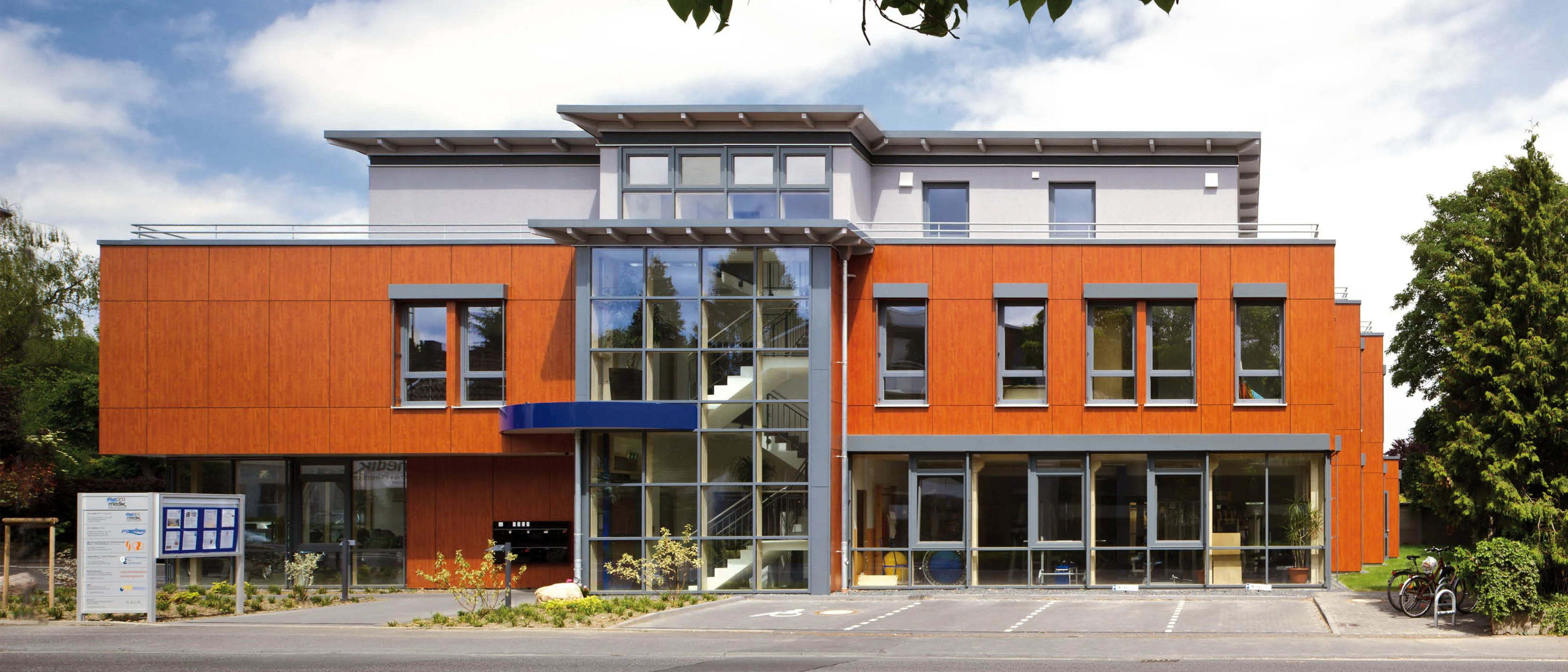 Moderne Bürogebäude mit Holzverkleidung und Glasfront, Treppenhaus im Zentrum.