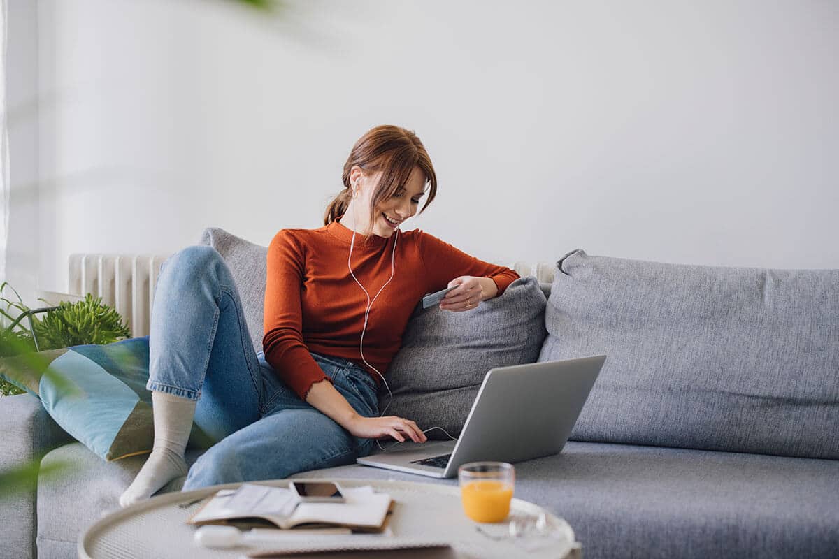 Young woman on sofa shopping online with credit card