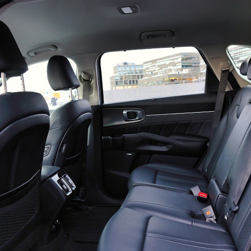 Rear seats of a modern car with black interior and city buildings visible through the windows.