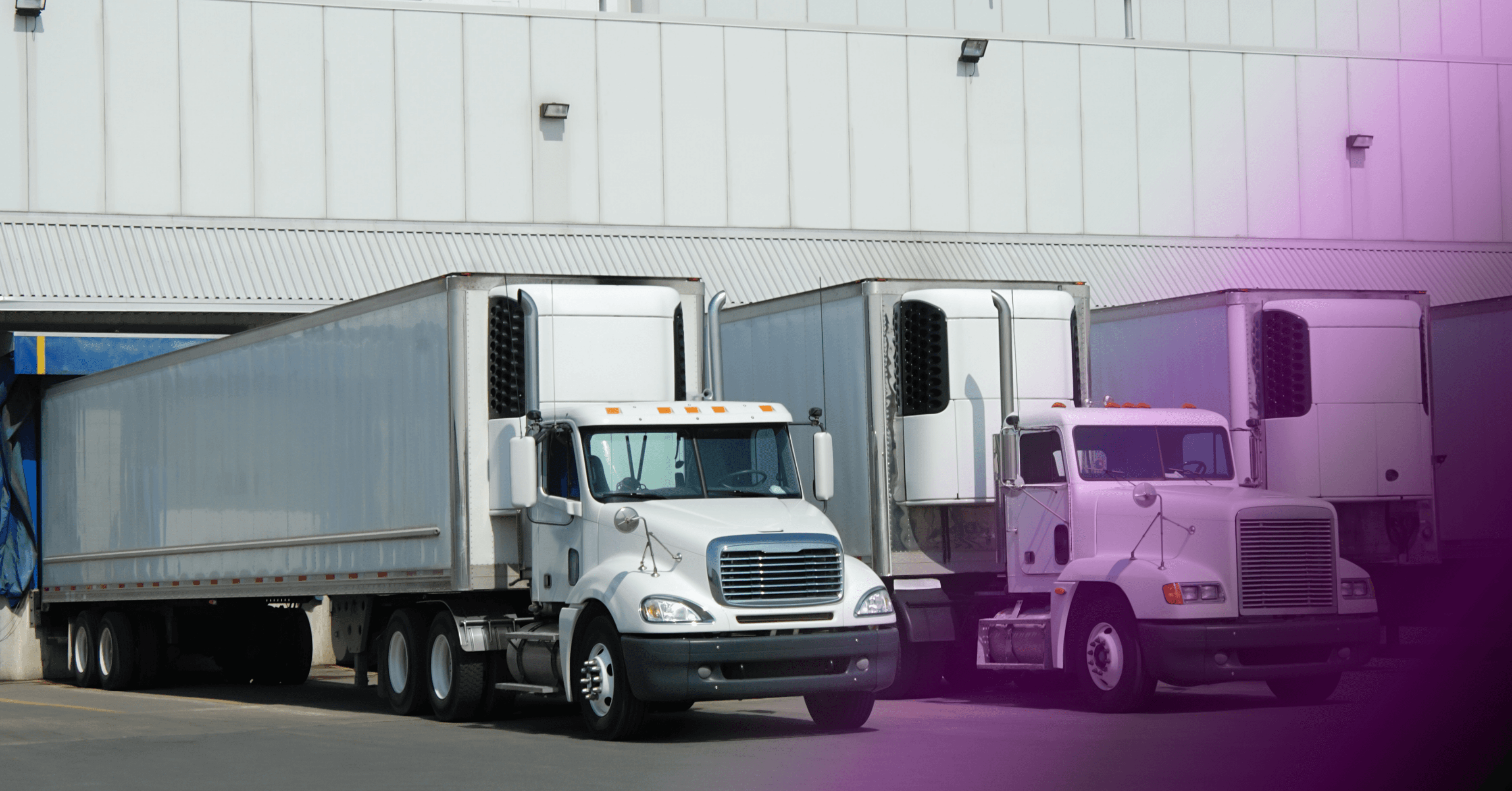 Fleet of commercial semi-trucks parked at a warehouse loading dock for freight distribution.