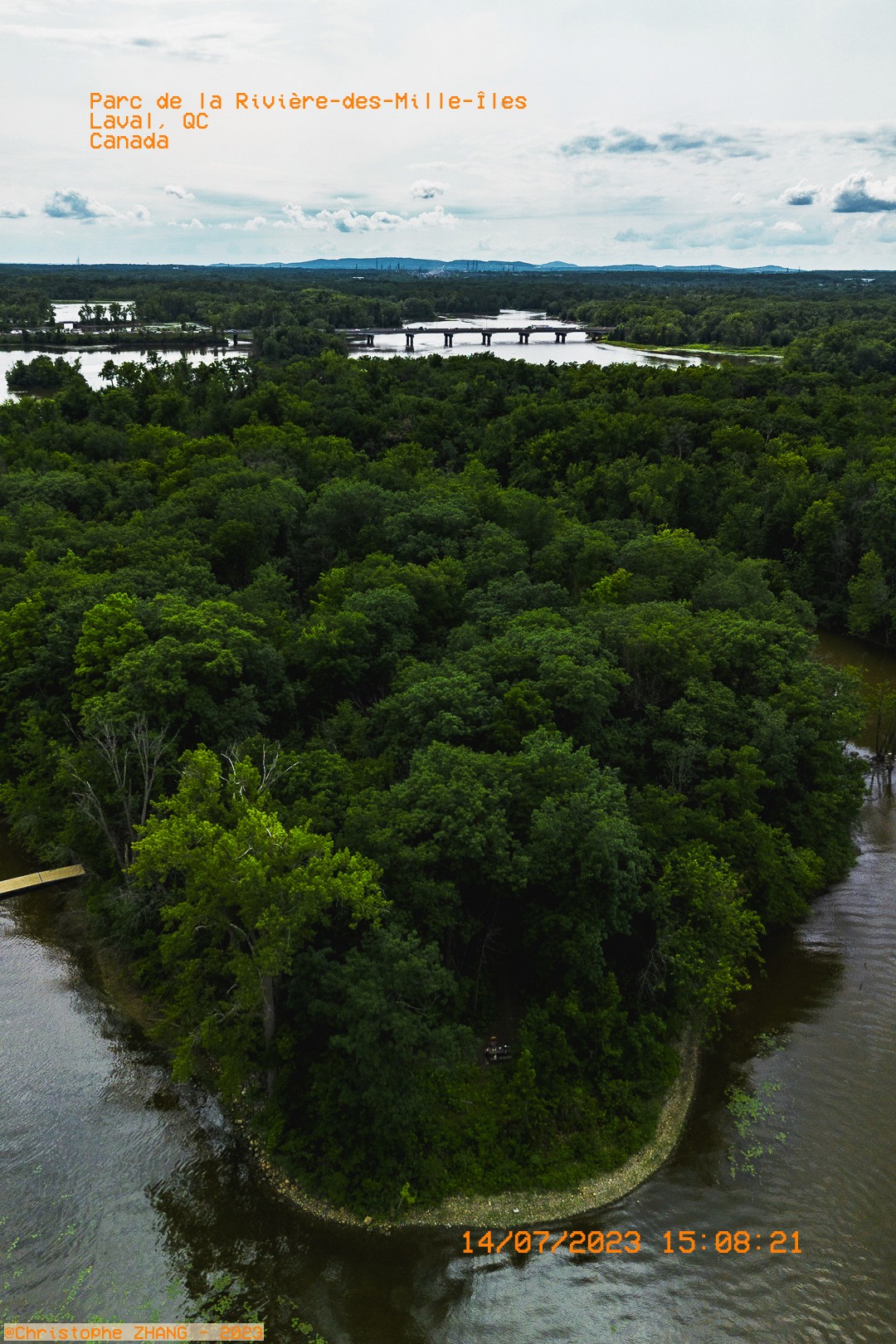 Vue aérienne du Parc de la Rivière-des-Mille-Îles à Laval, avec une forêt dense entourée d'eau.