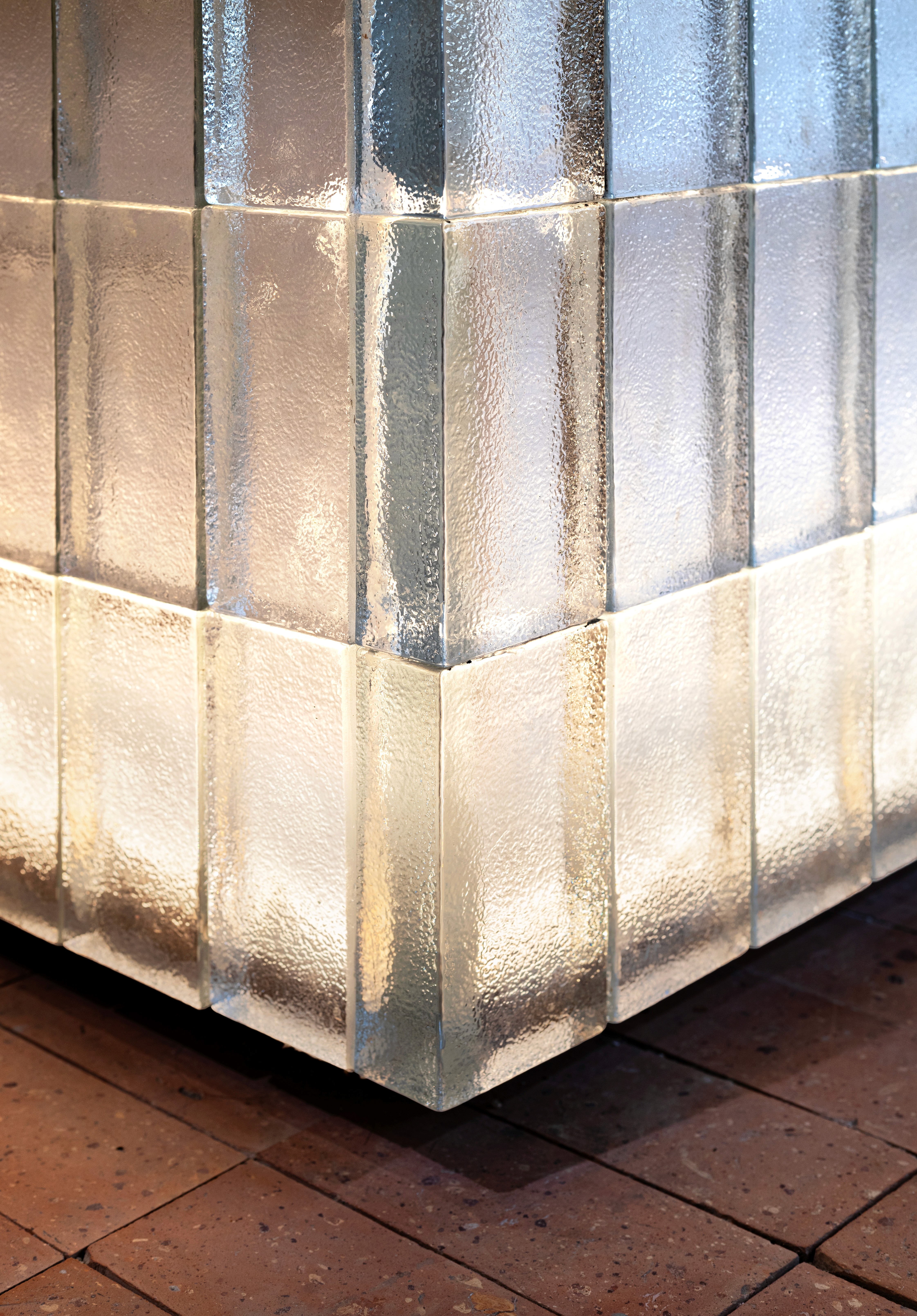 Corner detail of modular glass block screen with reflected lighting, engineered glazing assembly providing luminous effect and long-term material performance