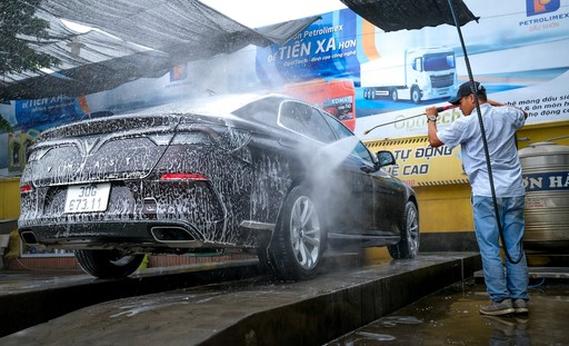 Car getting washed by person holding spray gun