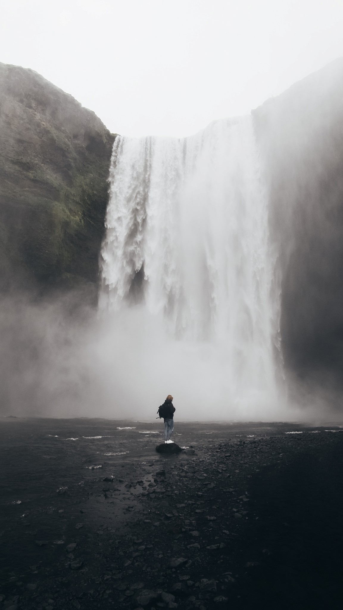 A guy standing in front of a waterfall