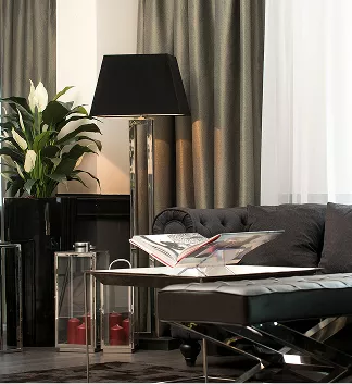 Aufnahme des Loungebereichs bei der Rezeption mit Sofa im Hintergrund, Tisch mit Magazin und einer gemütlichen Stehlampe