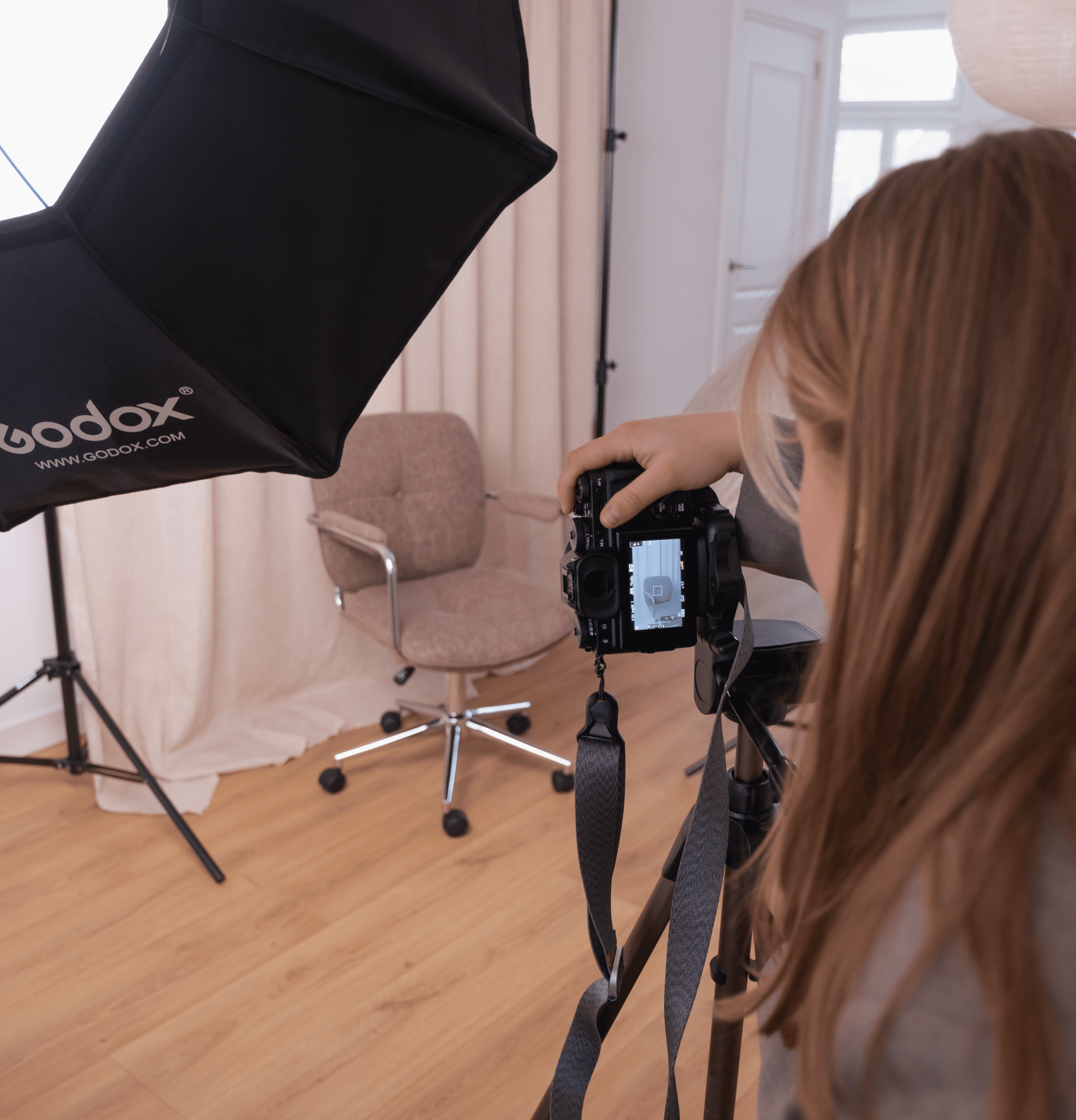 A smiling couple takes a selfie under a clear blue sky. The woman wears a red jacket, and the man, in a green top, holds a smartphone.
