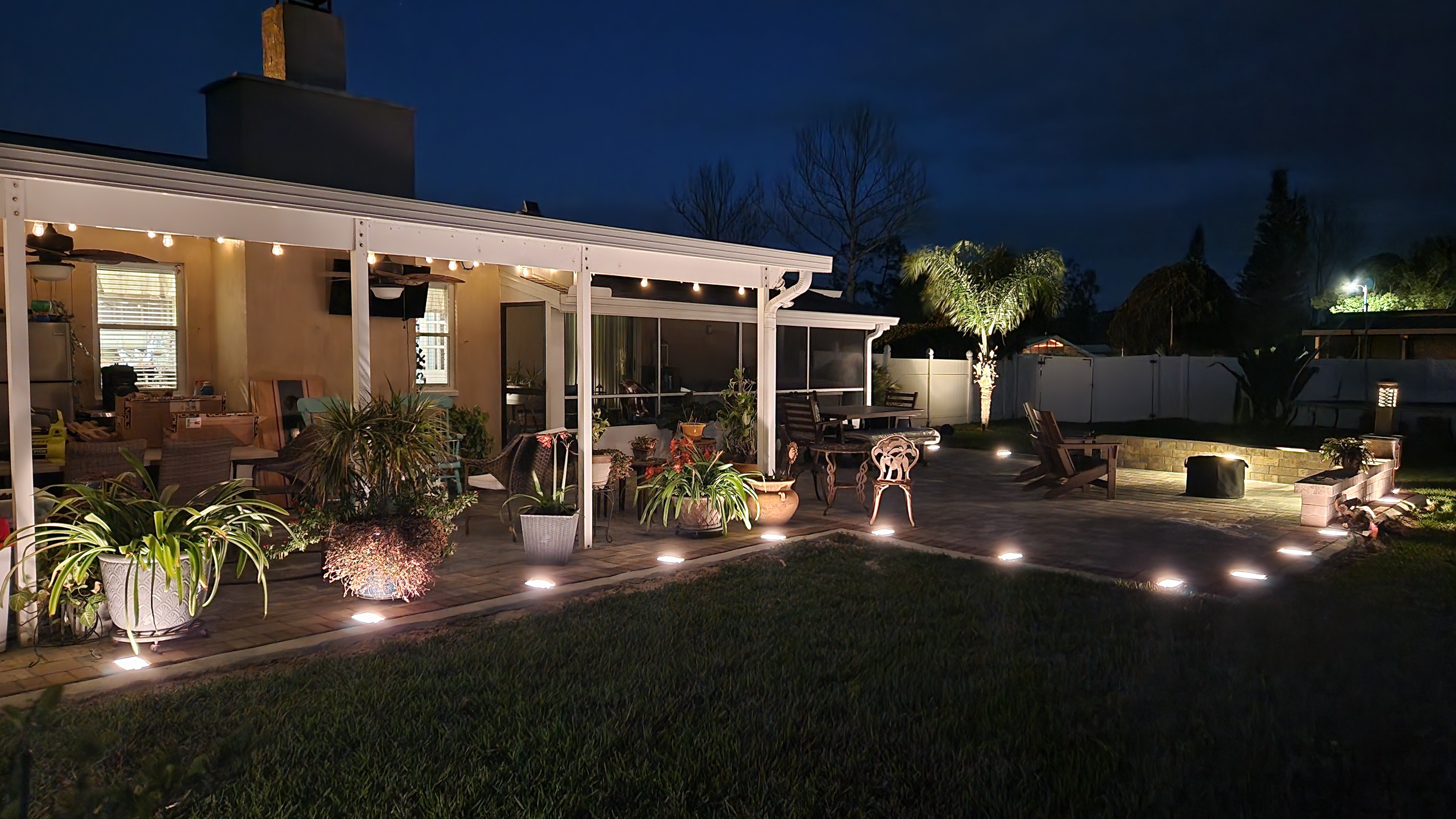 Backyard pathway and patio illuminated with low-profile landscape lighting fixtures
