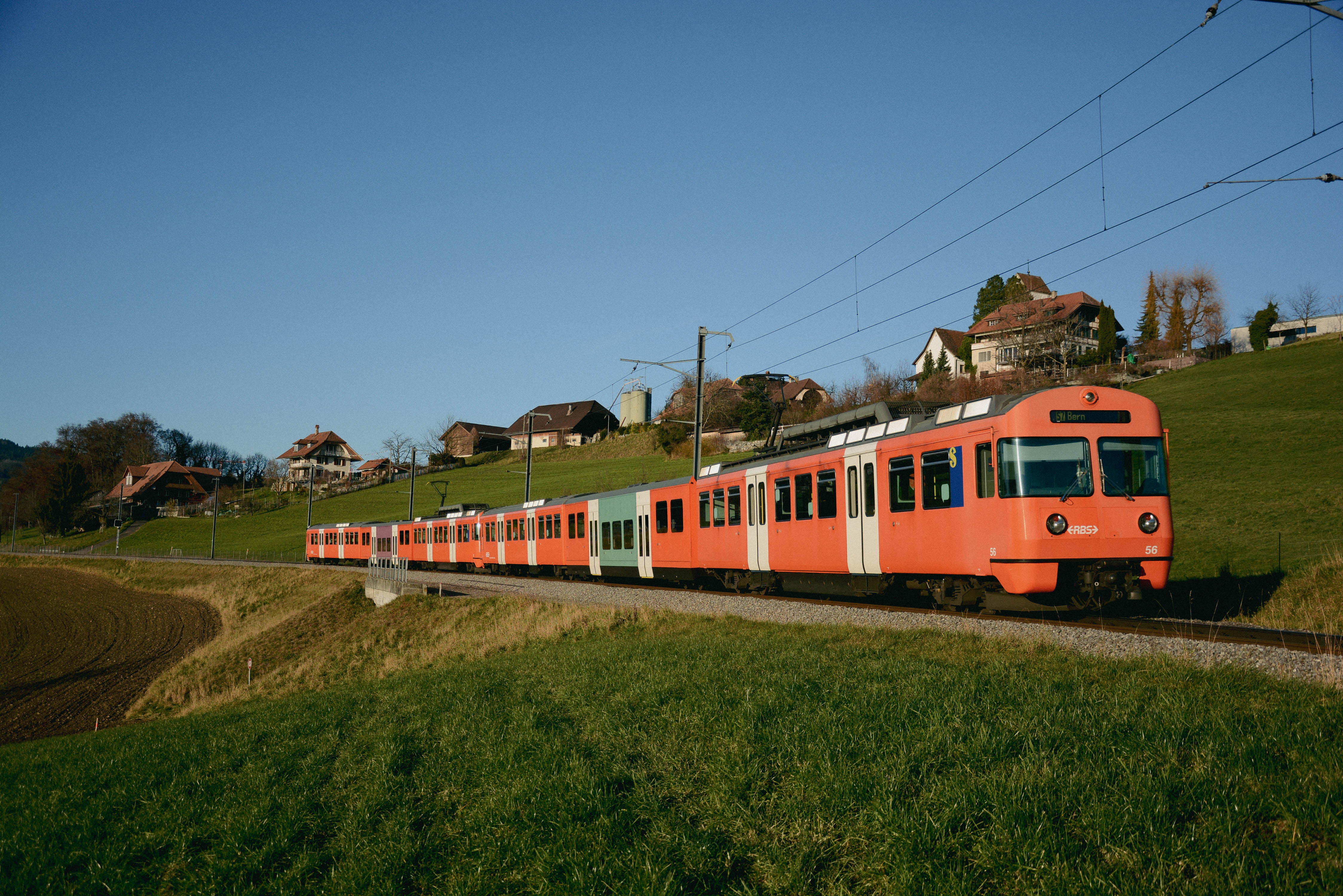 Der orangene Zug Mandarindli vom RBS auf dem ländlichen Streckennetz der Region Bern. 