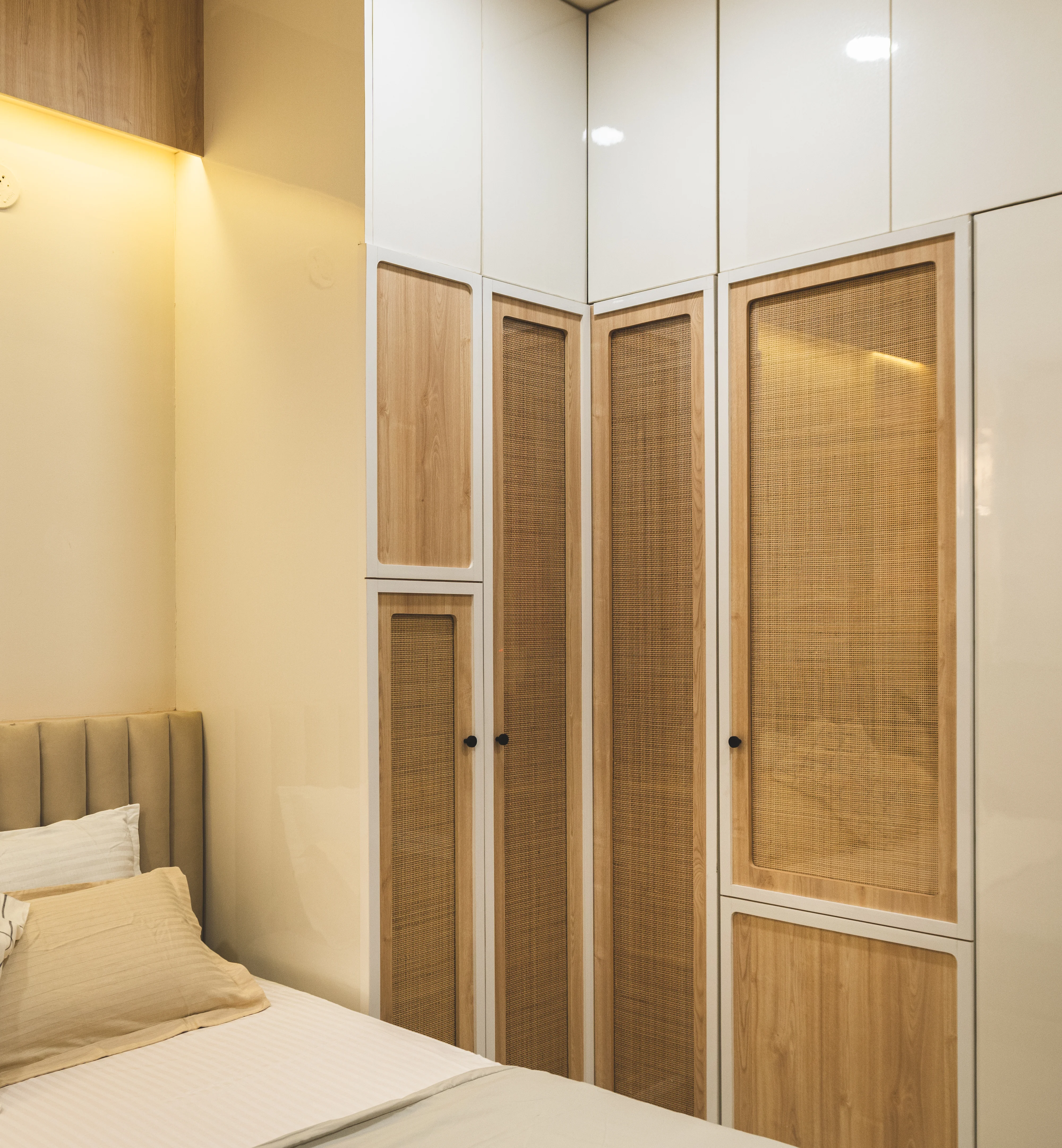 A well-furnished bedroom showcasing a comfortable bed, a spacious wardrobe, and a mirror enhancing the decor.