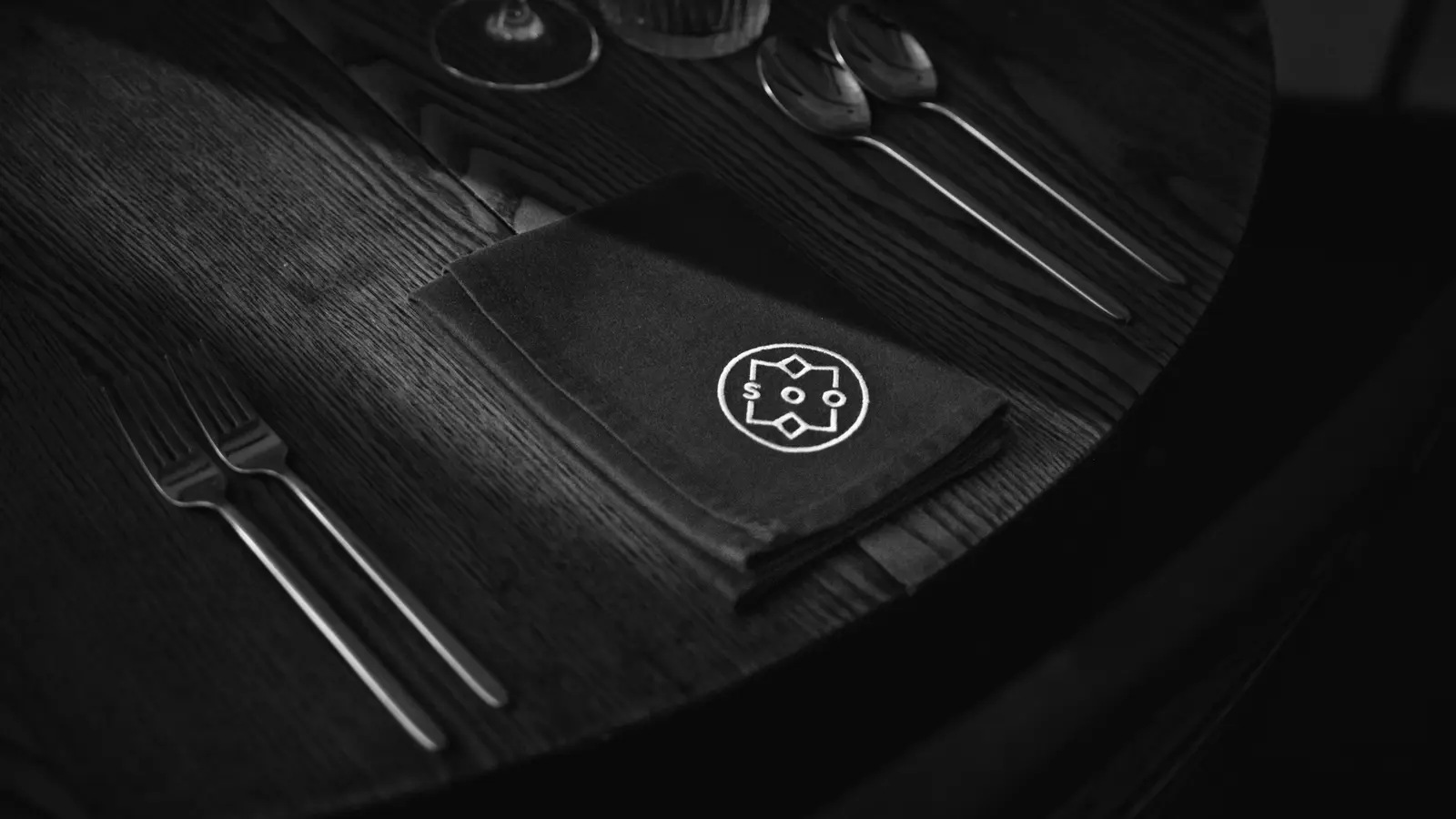 Table setting with the SOO restaurant logo embroidered on a black napkin