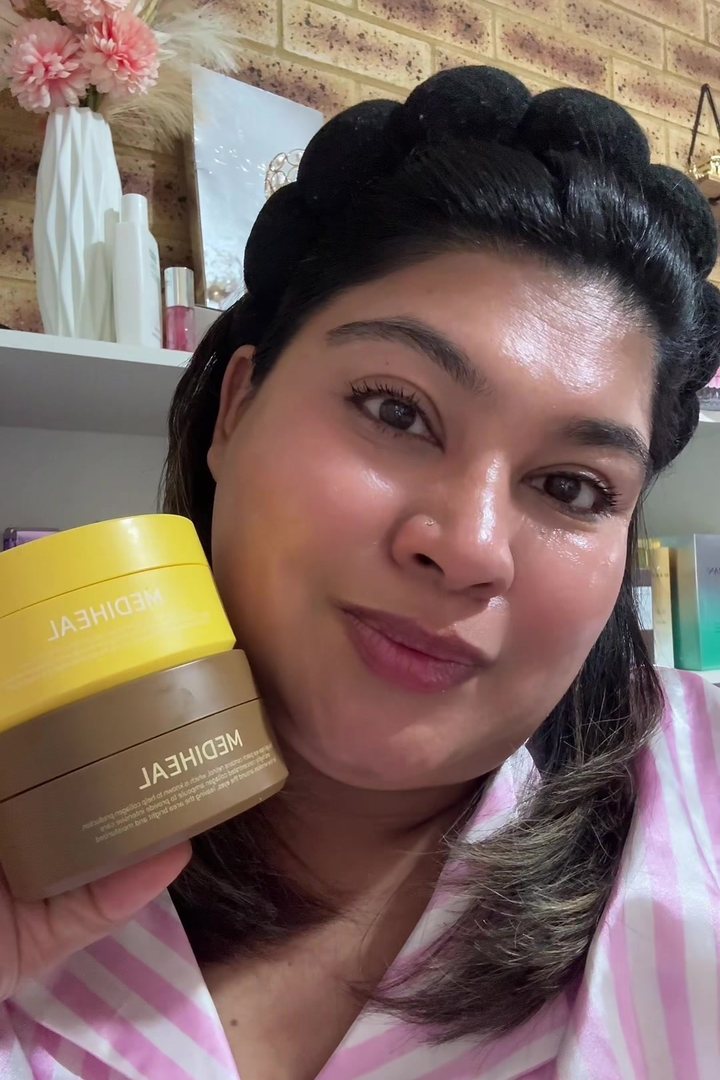 Option D: a creator holding stacked skincare tubs beside her face