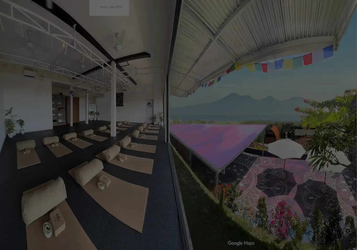 Spacious open-air yoga shala with panoramic ocean and mountain views set up with mats and props for teacher training classes at Ulu Yoga Bali.