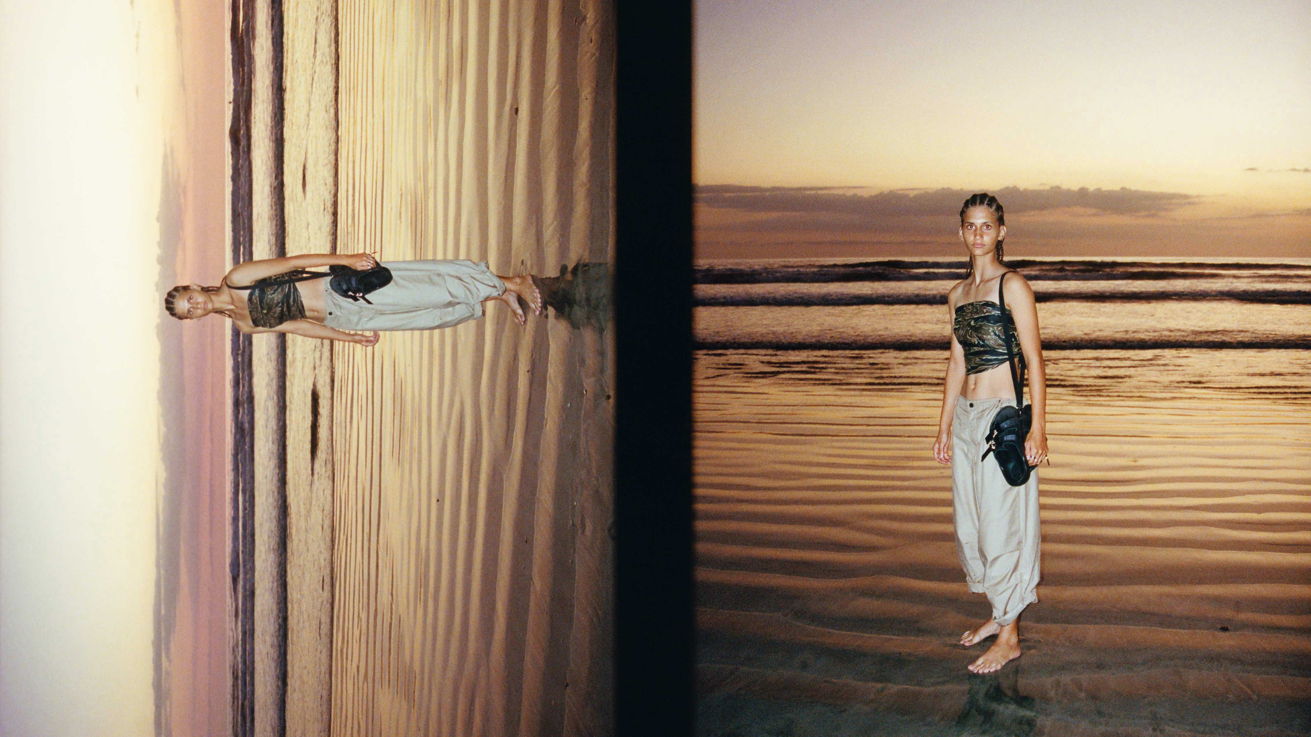 A lone figure stands at the shoreline, their full-body reflection cast across the glistening sand—an image that mirrors Birkenstock 1774’s fusion of timeless heritage with modern elegance.