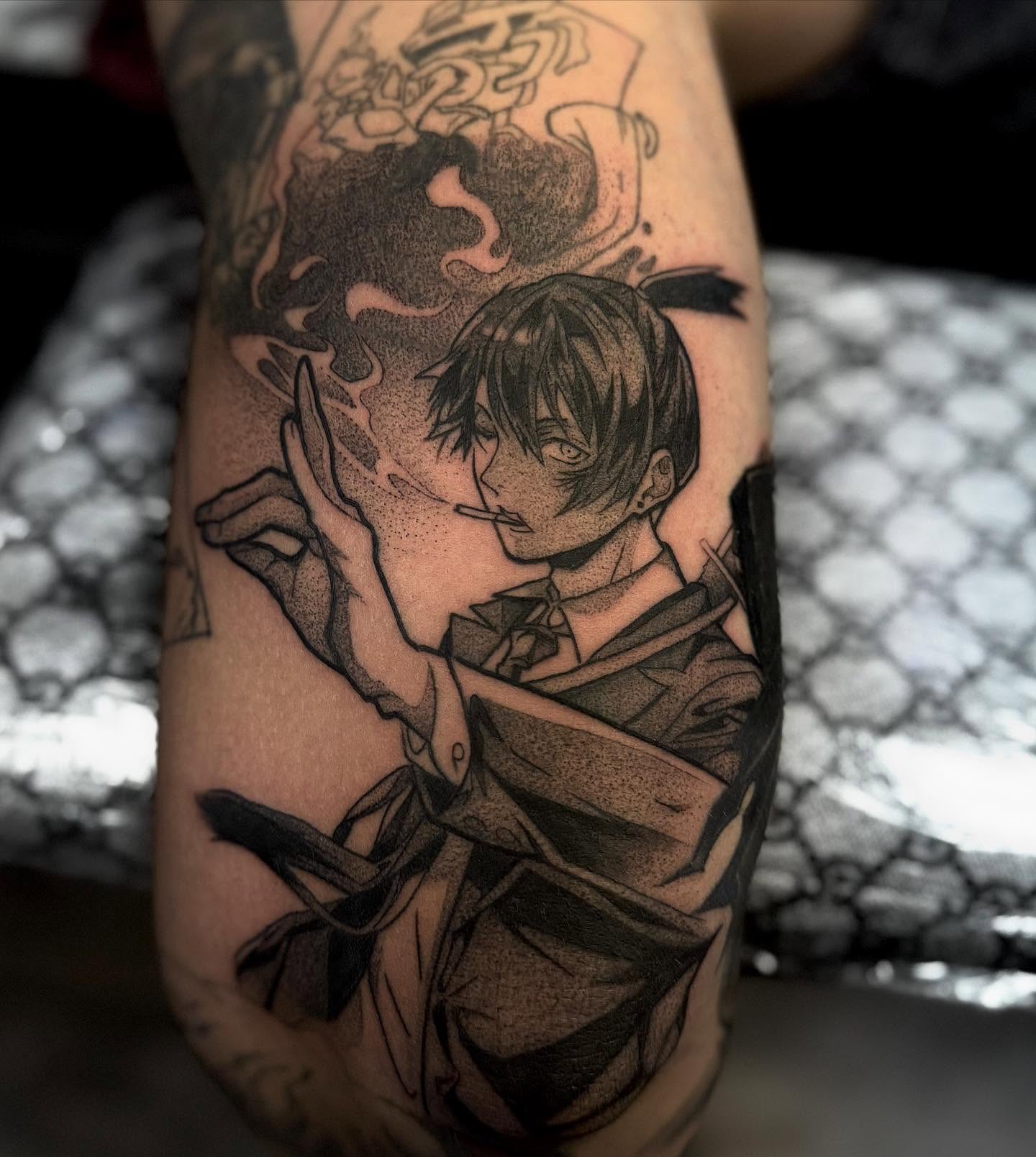 A grayscale anime-style tattoo of a character with spiky hair and a headband, holding a kunai.  The tattoo is on someone's forearm.