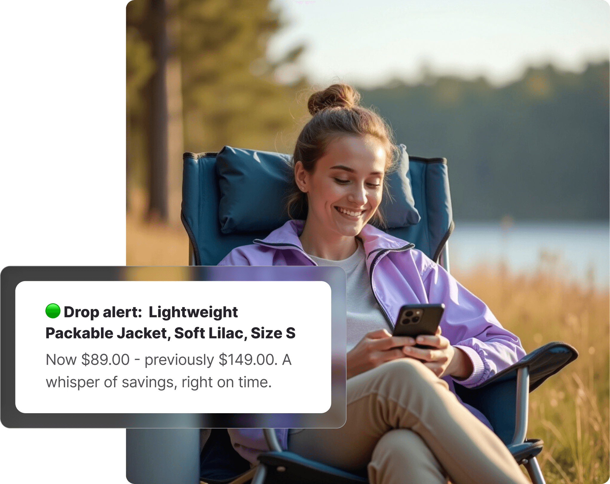 Woman in a purple lululemon-style windbreaker sitting in a camp chair outdoors by a lake, smiling at her phone with tall grass and trees in the background.
