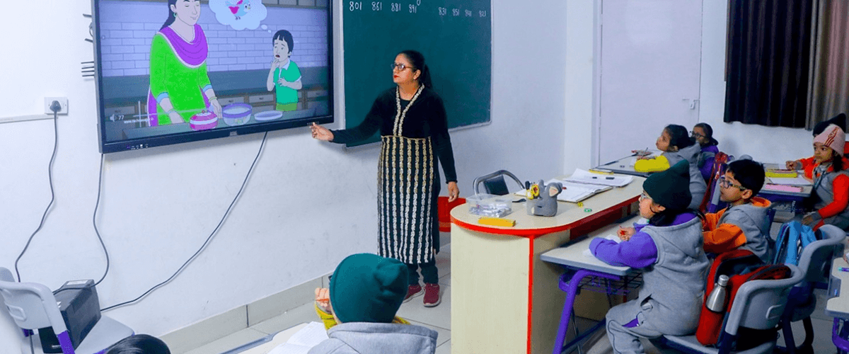 A teacher using an interactive screen to play an animated educational video for students, representing the use of video production in education.