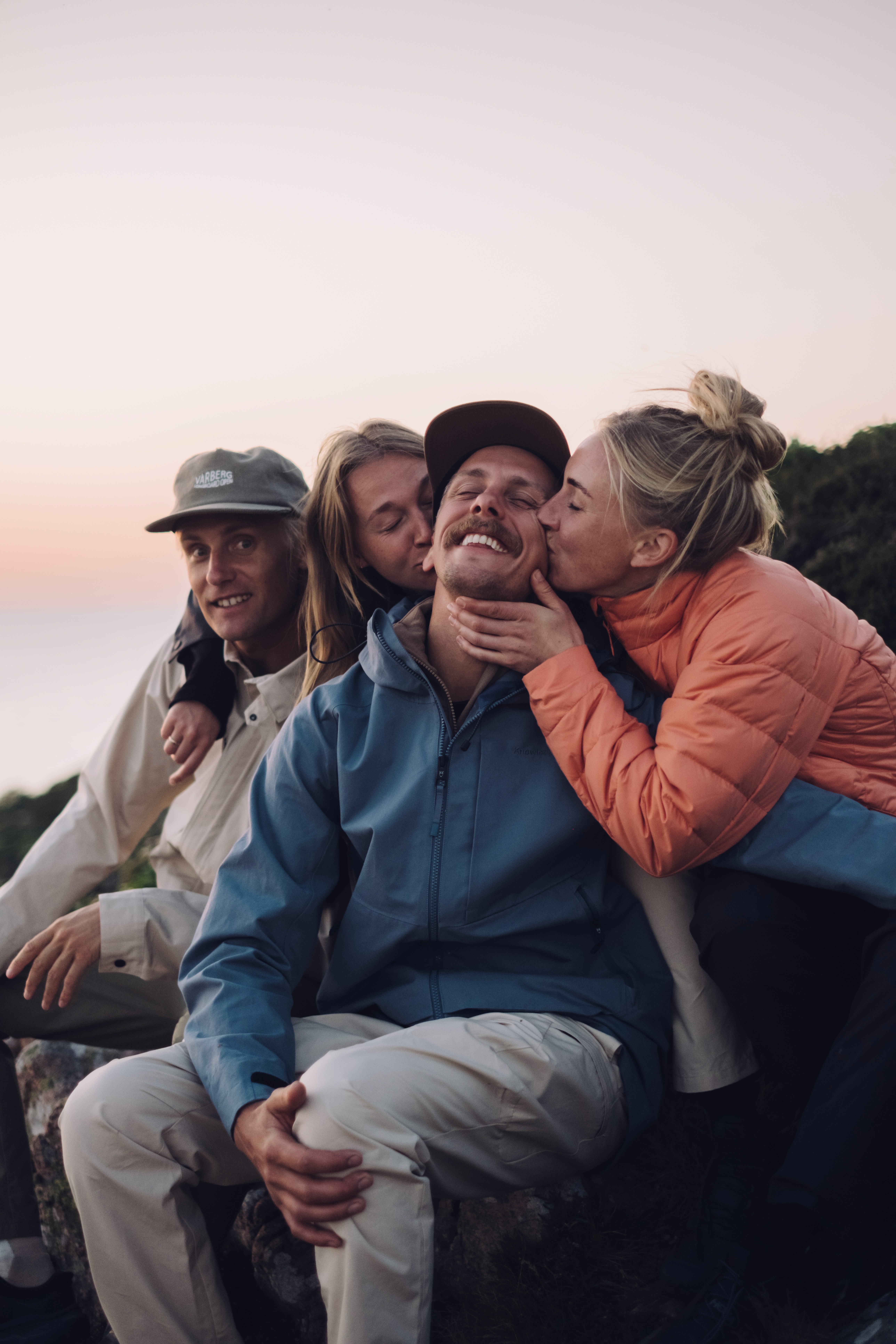 4 amis vêtus en Knowledge Cotton Apparel assistent à un coucher de soleil