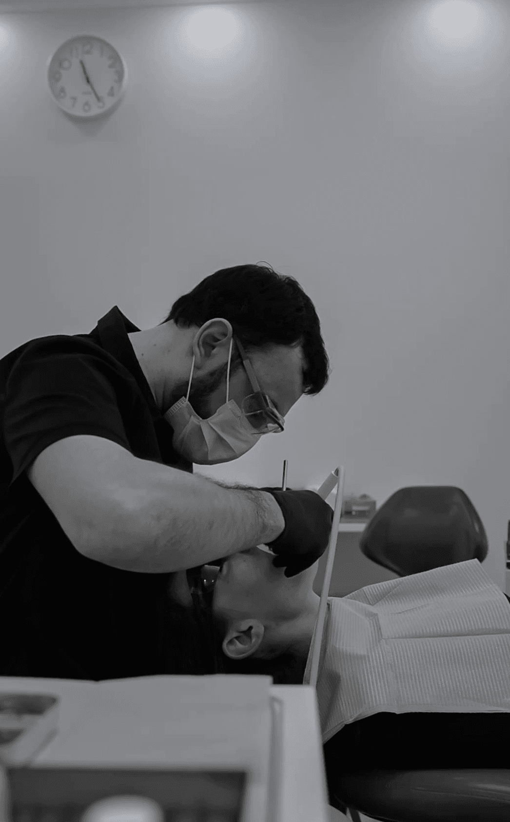 Zahnarzt in Maske und Handschuhen behandelt Patient mit zahnärztlichem Werkzeug.